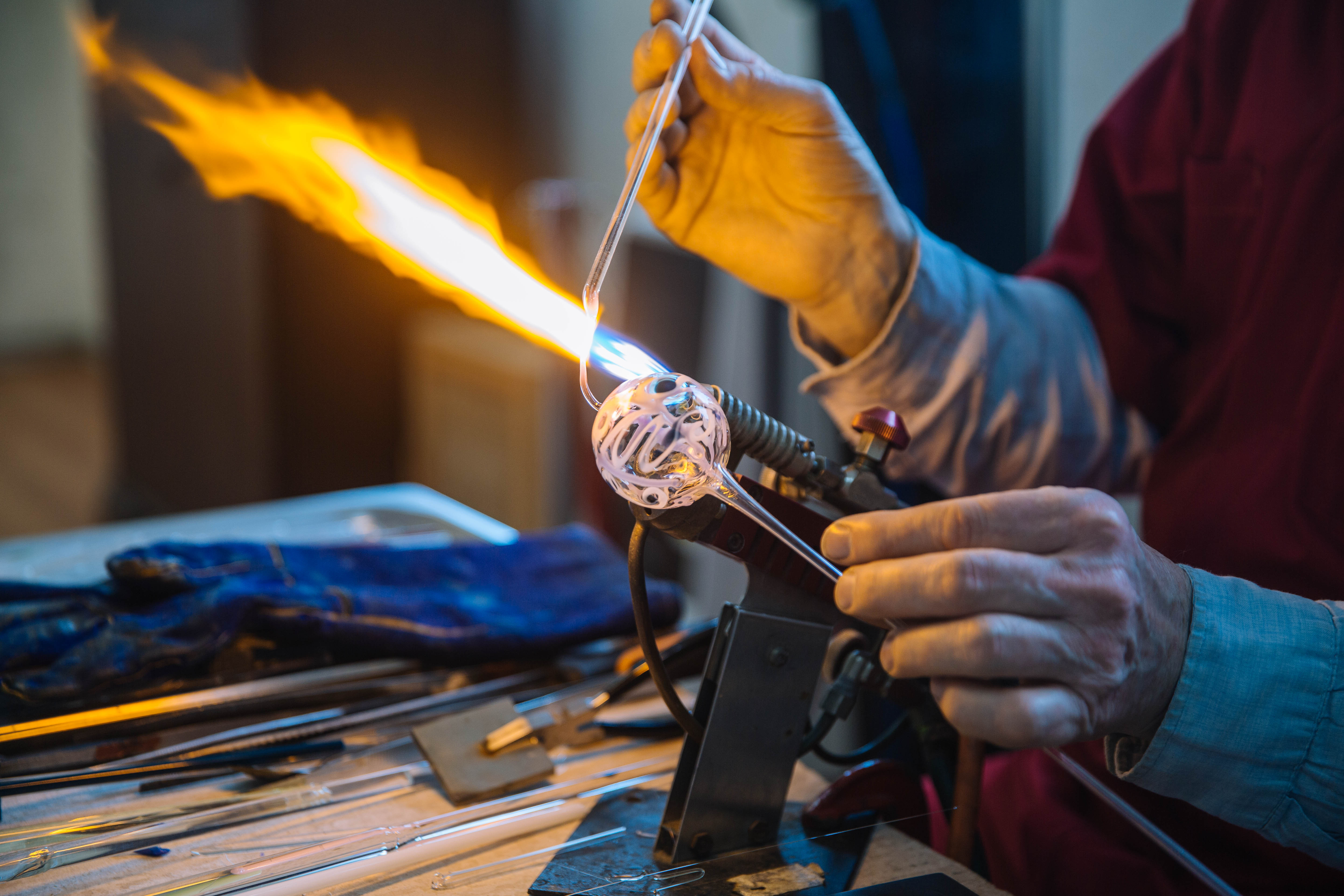 Hand holding a glass-blown ornament up to a flame